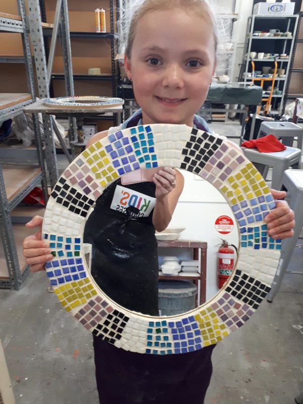 Child holding a mirror with a mosaic border